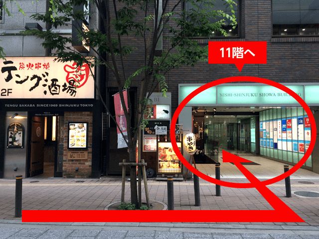 向かい側の「炭火串焼テング酒場」が見えたら、その右手にある「西新宿昭和ビル(NISHI‐SHINJUKU SHOWA BUILDING)」​の11階です。