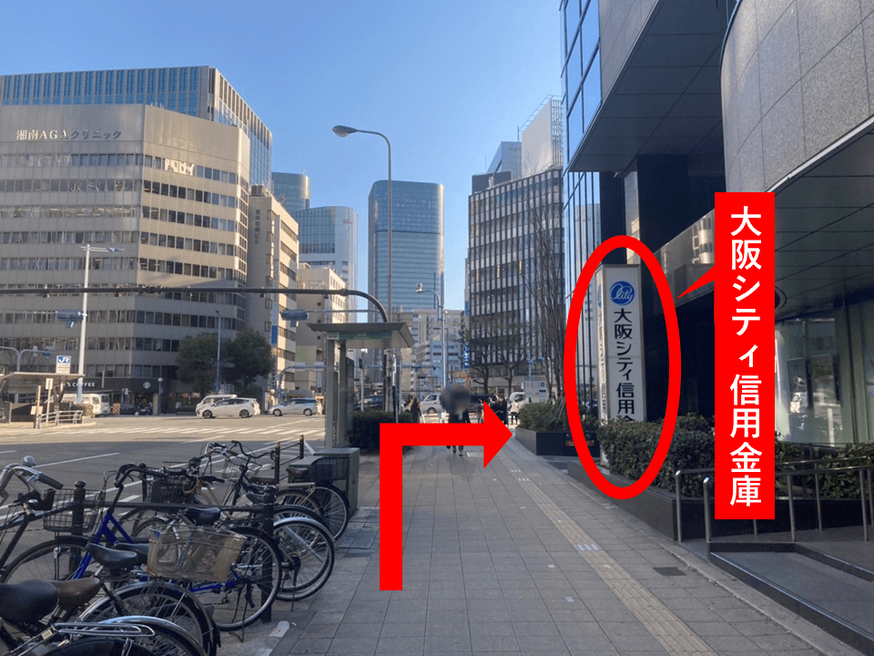 横断歩道を1つ渡り直進すると、1階に「大阪シティ信用金庫」が入ったビルが見えてきますのでそのまま直進し、横断歩道の手前で右に曲がってください。